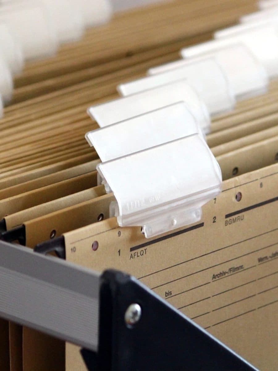 Hanging file folders with blank index tabs in an open drawer.